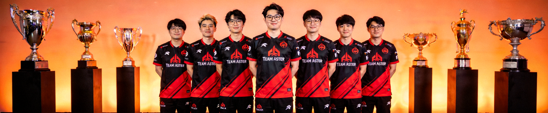 知名电竞战队Team Aster全体队员身着队服合影，背景为冠军奖杯